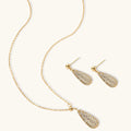 Gold necklace and earrings set on a white background