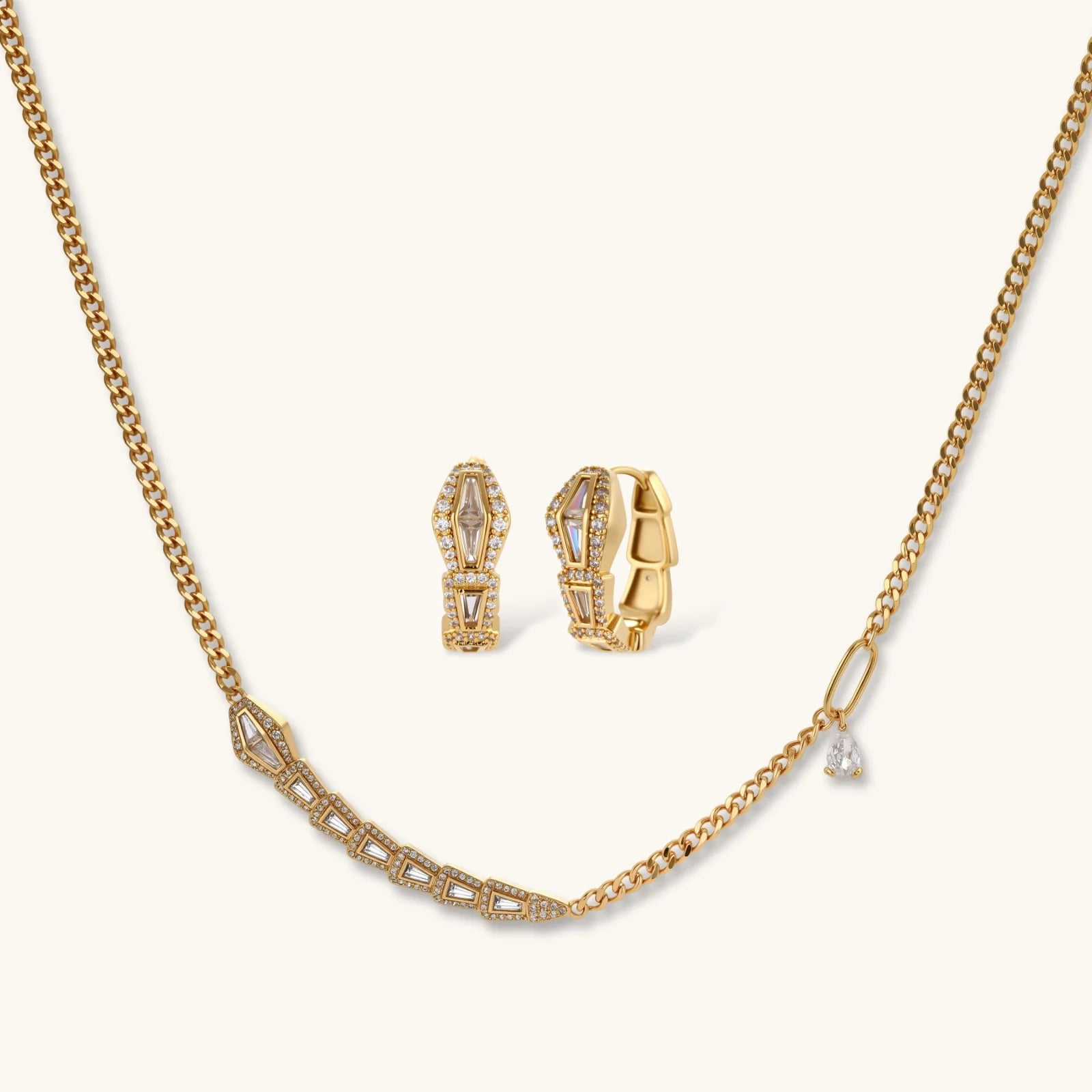 Gold geometric serpentine necklace and earrings set with zirconia sparkle on a white background