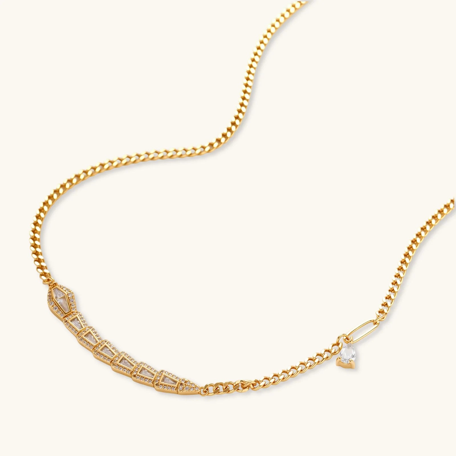 Gold necklace with a curb chain and serpentine pendant on a white background