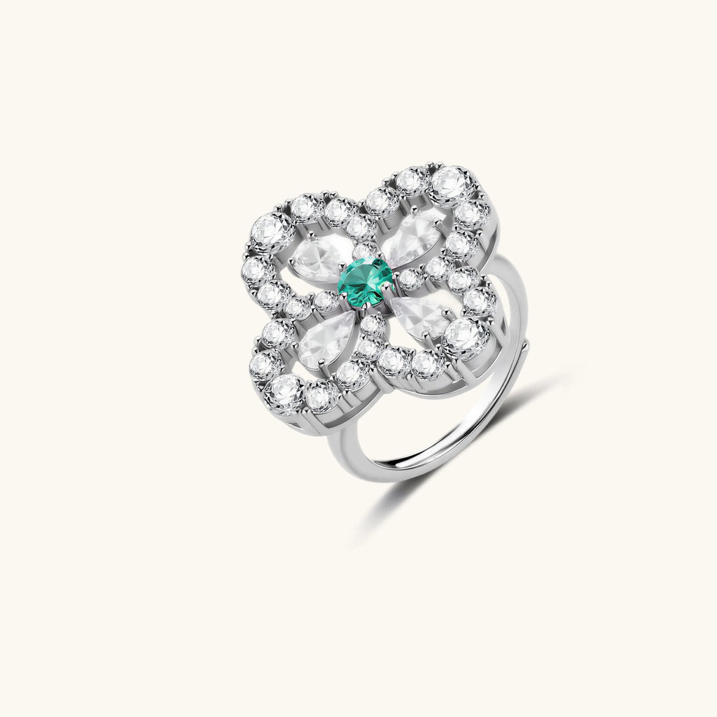 Silver ring with floral design and green gemstone on a white background