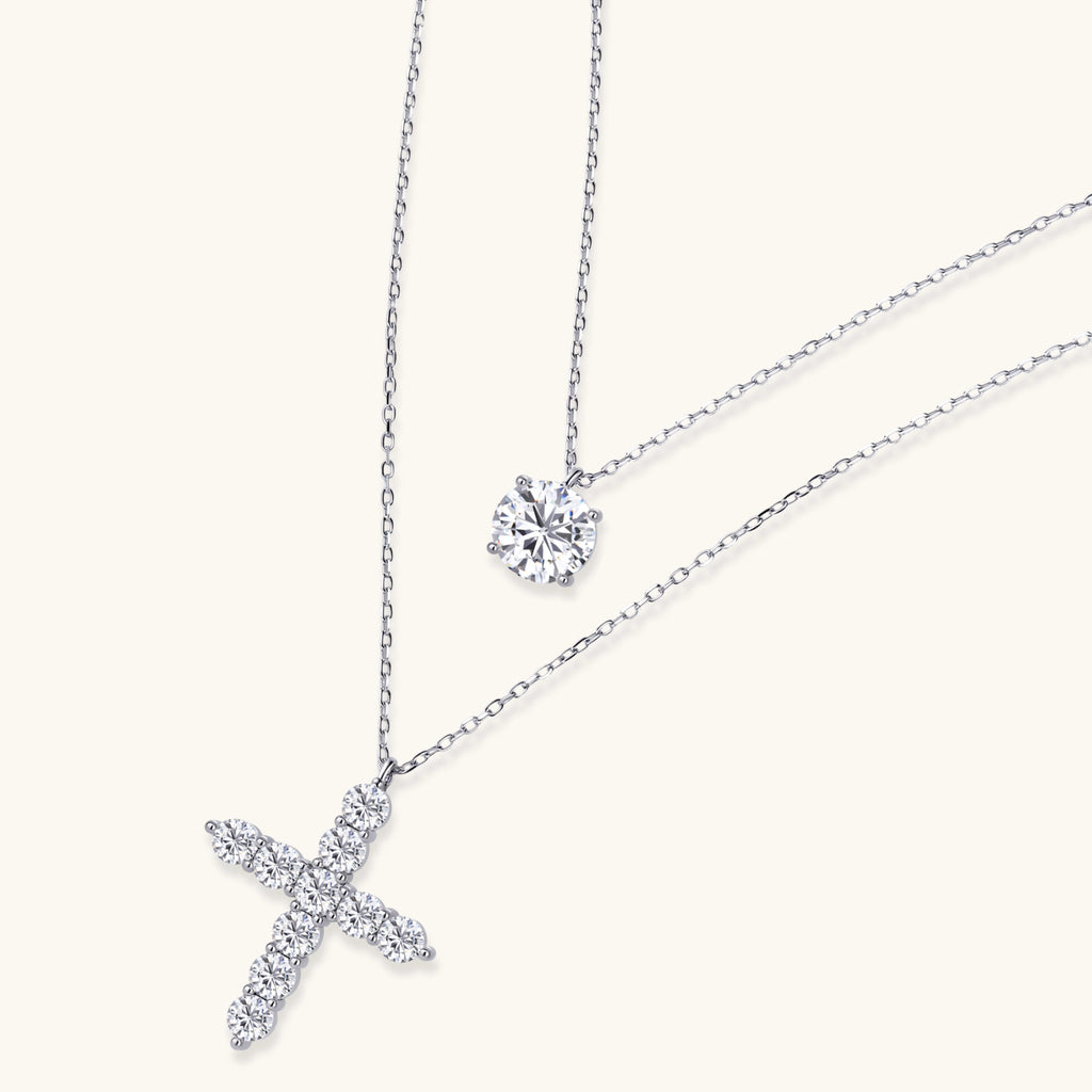 Diamond cross necklace and round diamond earring on a white background