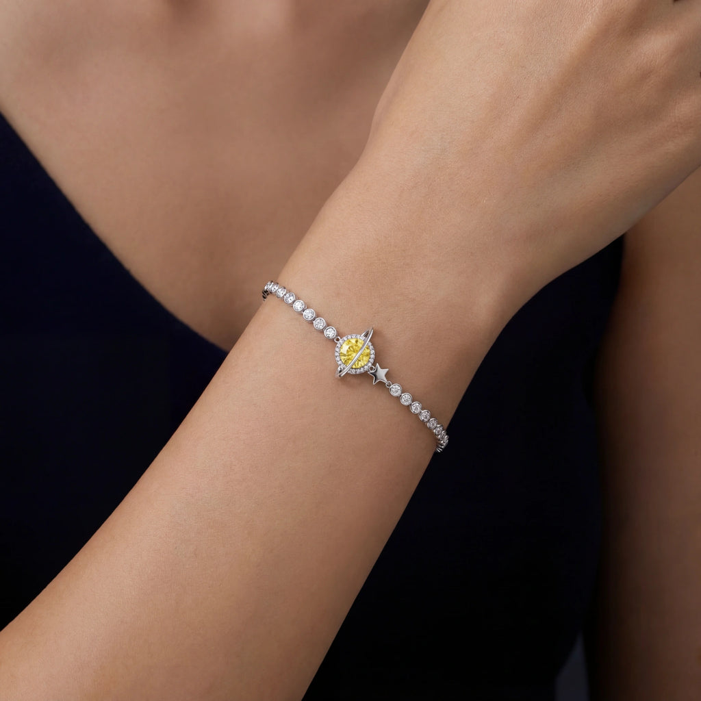 Silver bracelet with a yellow gemstone on a person's wrist against a dark background