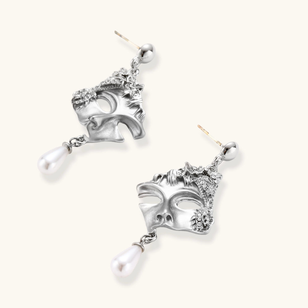 Silver mask earrings with pearl drops on a white background
