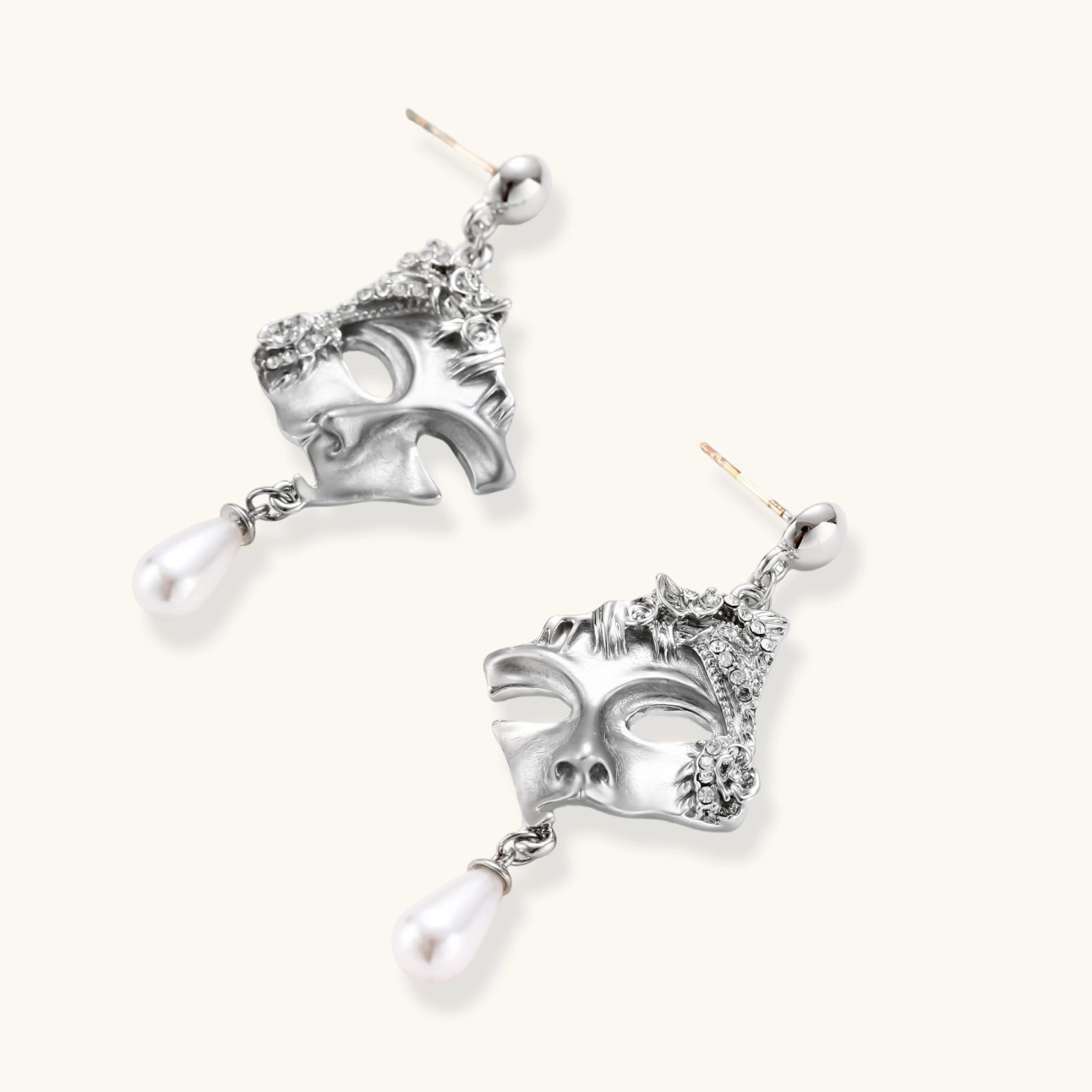 Silver mask earrings with pearl drops on a white background