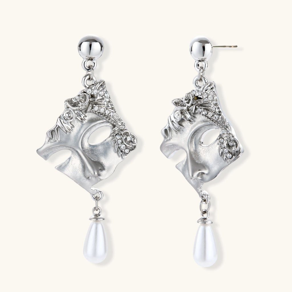 Pair of silver earrings with intricate designs and pearl-like elements on a white background