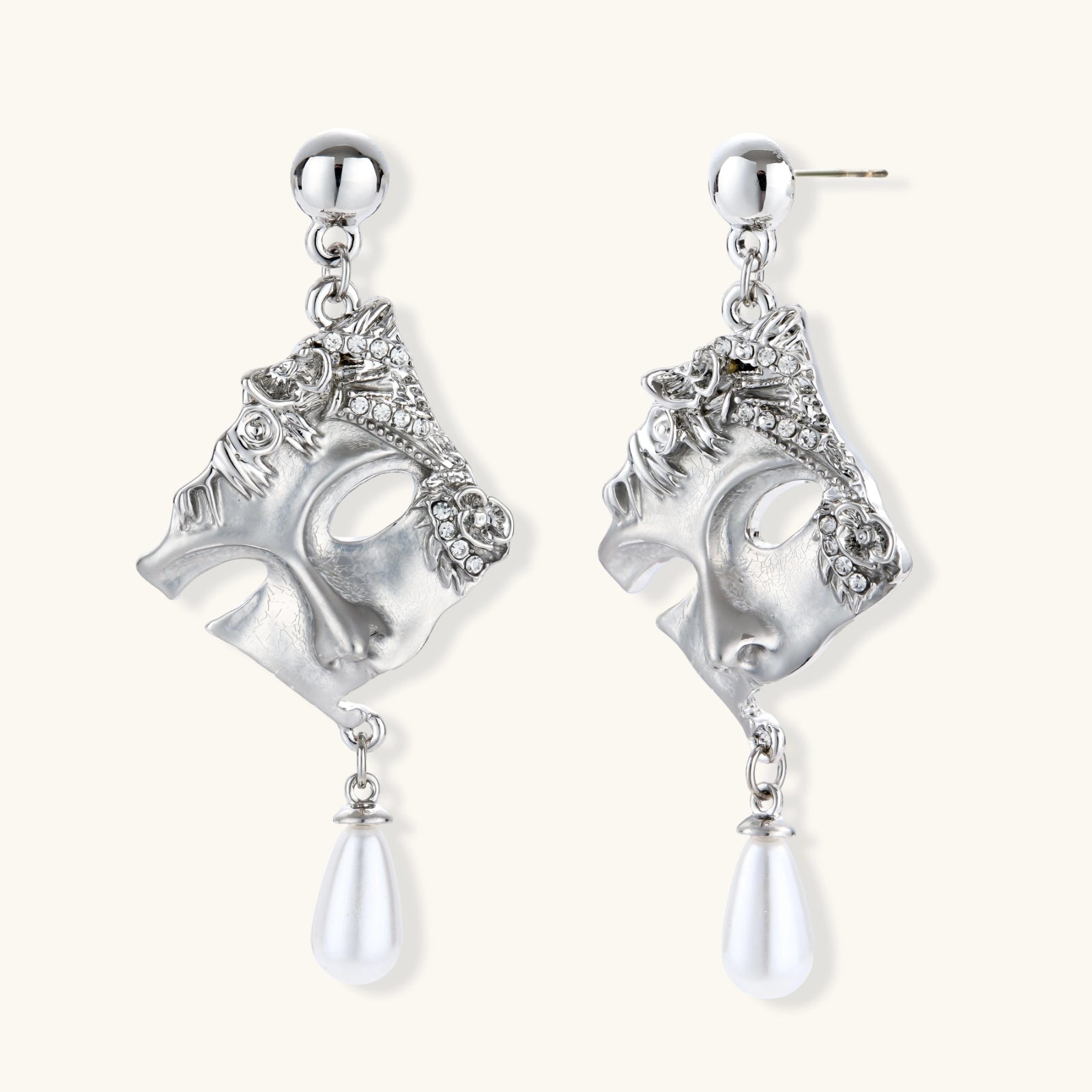 Pair of silver earrings with intricate designs and pearl-like elements on a white background
