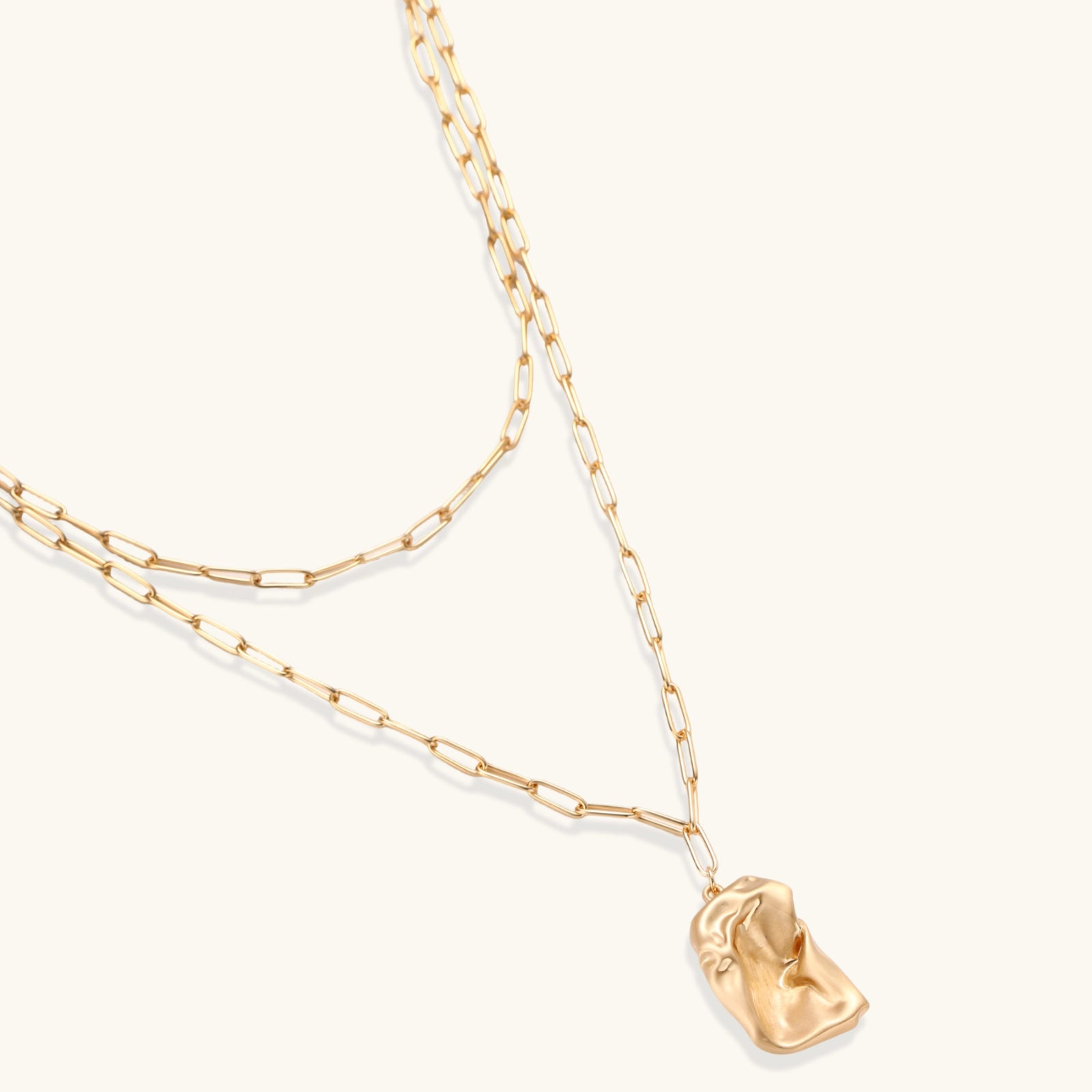 Gold necklace with a small pendant on a white background