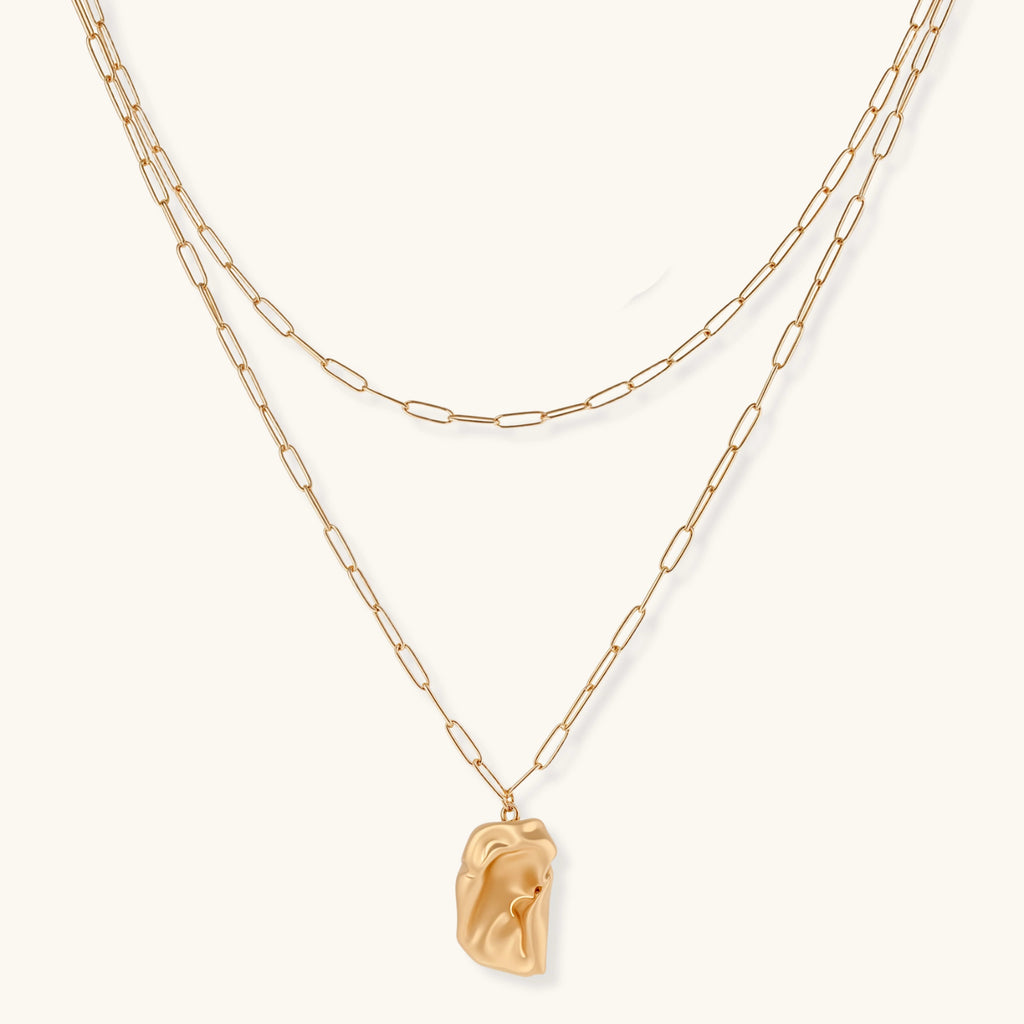 Gold chain necklace with a pendant on a white background