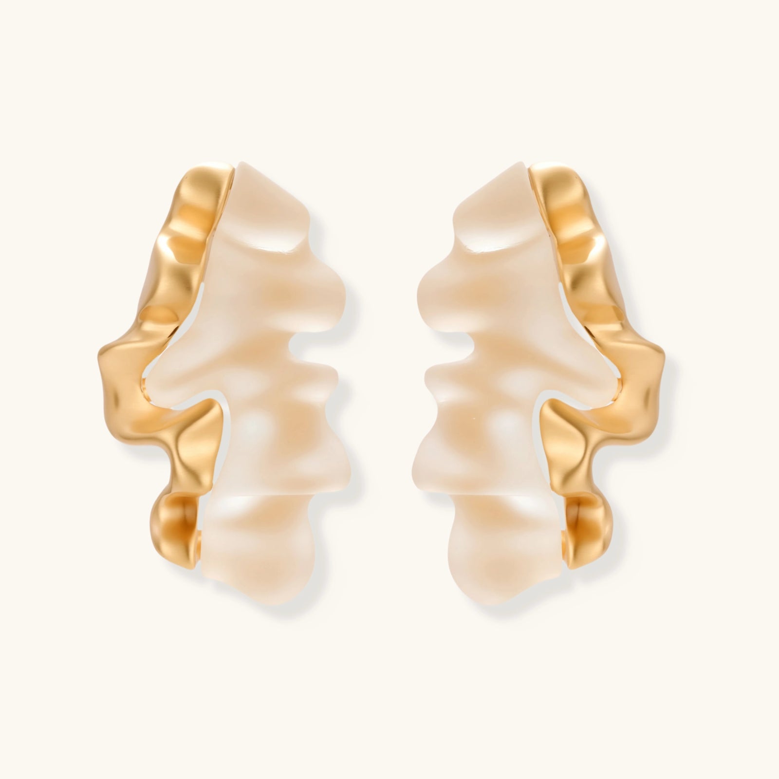 Pair of earrings with gold and beige design on a white background