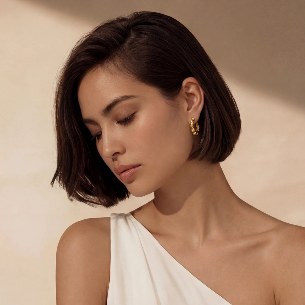 Woman wearing gold hoop earrings against a beige background