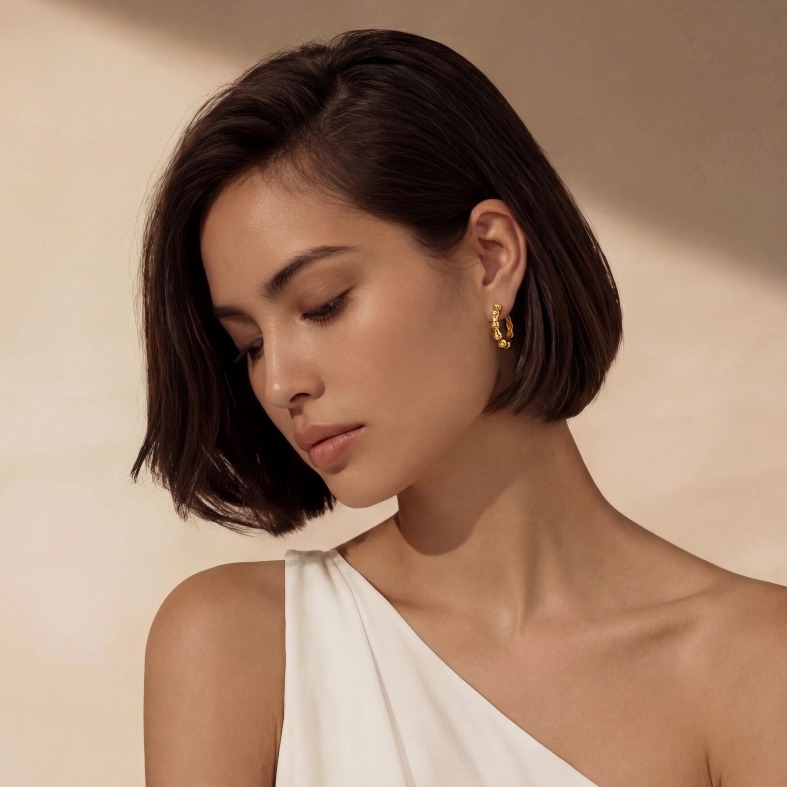 Woman wearing gold hoop earrings against a beige background