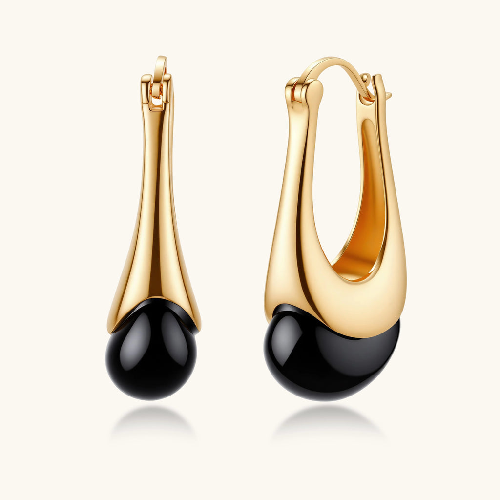 Gold hoop earrings with black beads on a white background