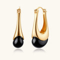 Gold hoop earrings with black beads on a white background