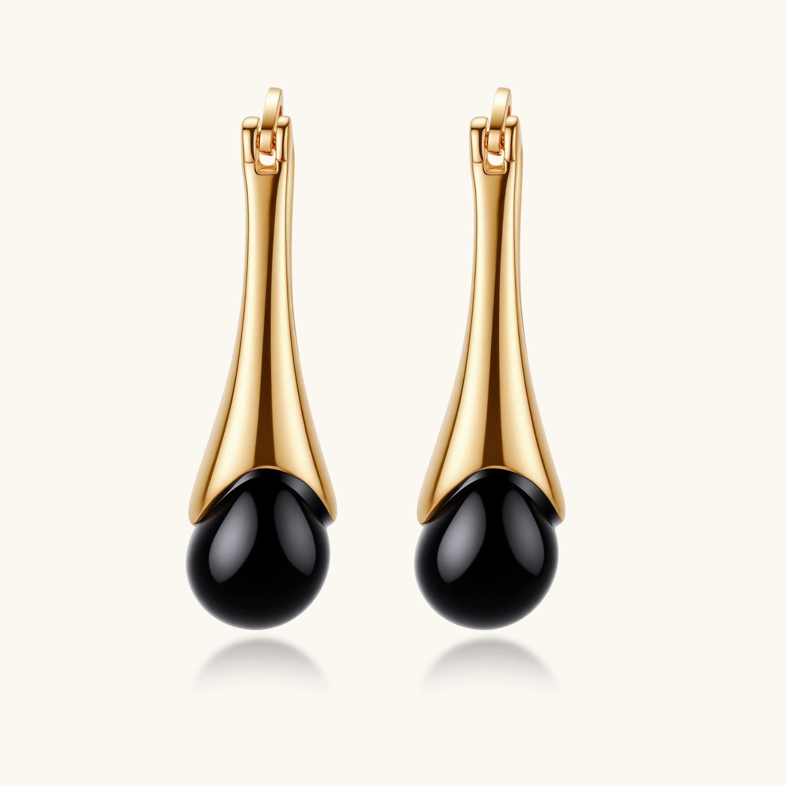 Gold earrings with black beads on a white background