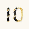 Pair of gold and black hoop earrings with diamond accents on a white background