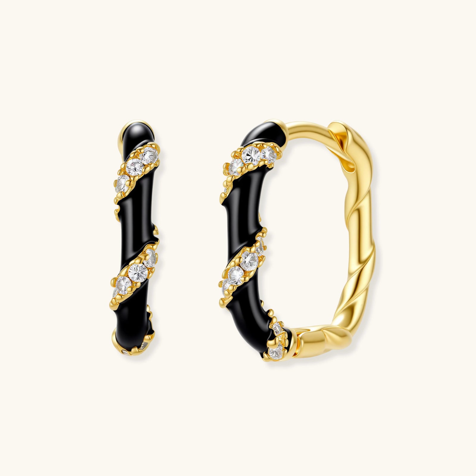 Pair of gold and black hoop earrings with diamond accents on a white background