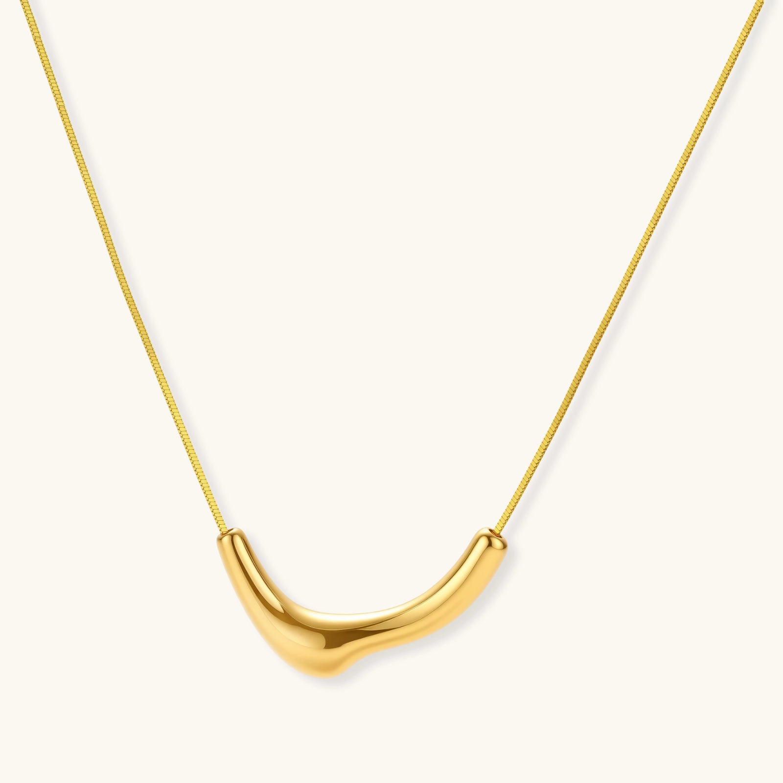 Gold necklace with a U-shaped pendant on a white background