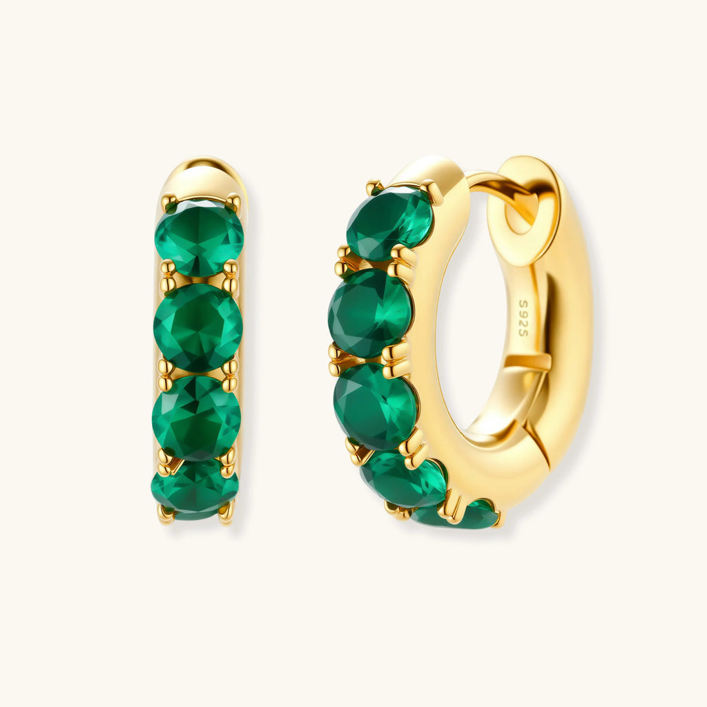 Gold hoop earrings with green gemstones on a white background