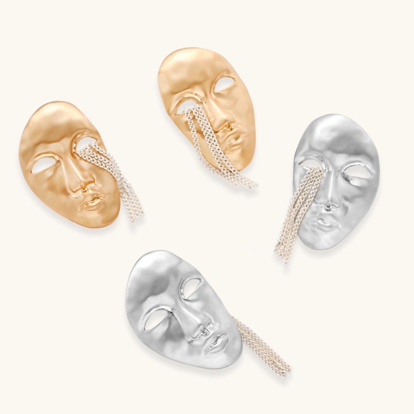 Gold and silver face-shaped earrings on a white background