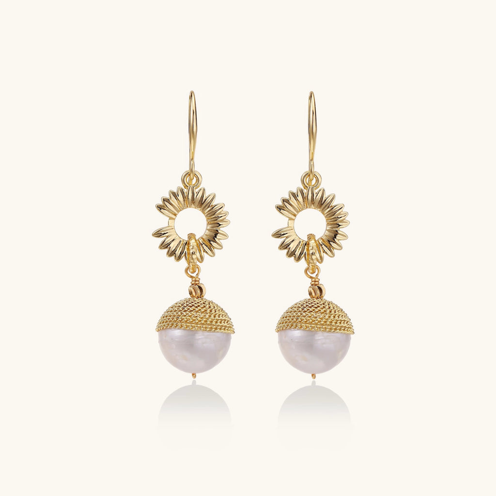 Gold earrings with pearl drops on a white background