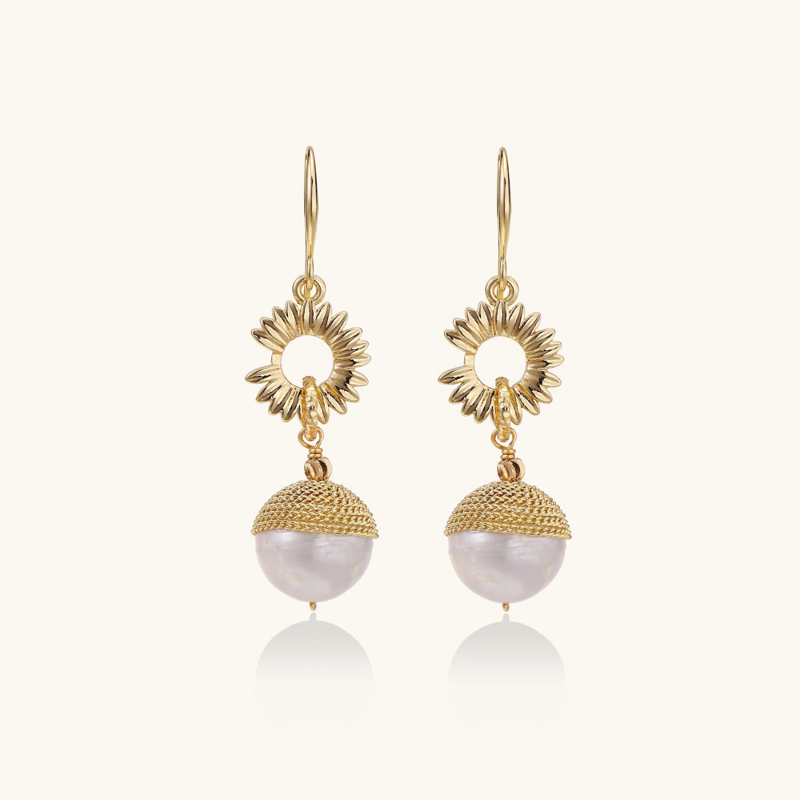 Gold earrings with pearl drops on a white background