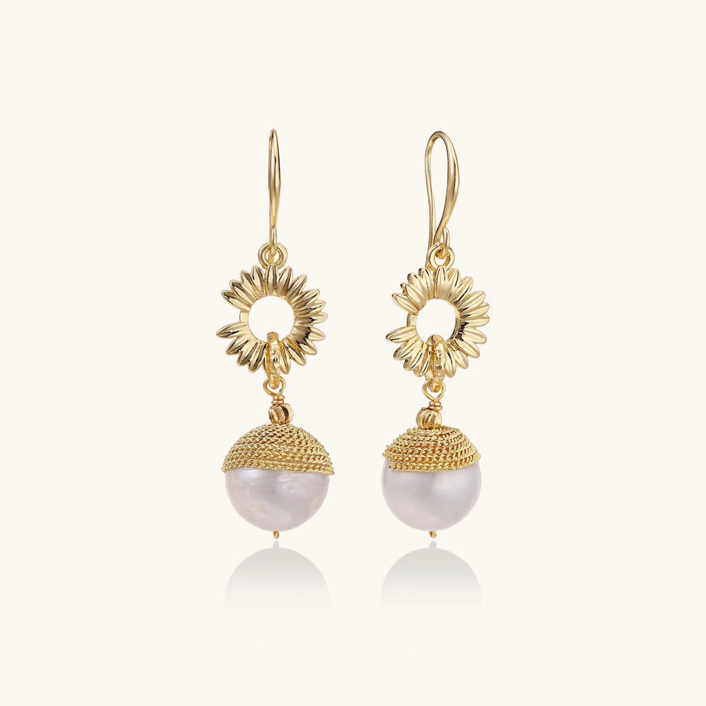 Gold earrings with pearl drops on a white background