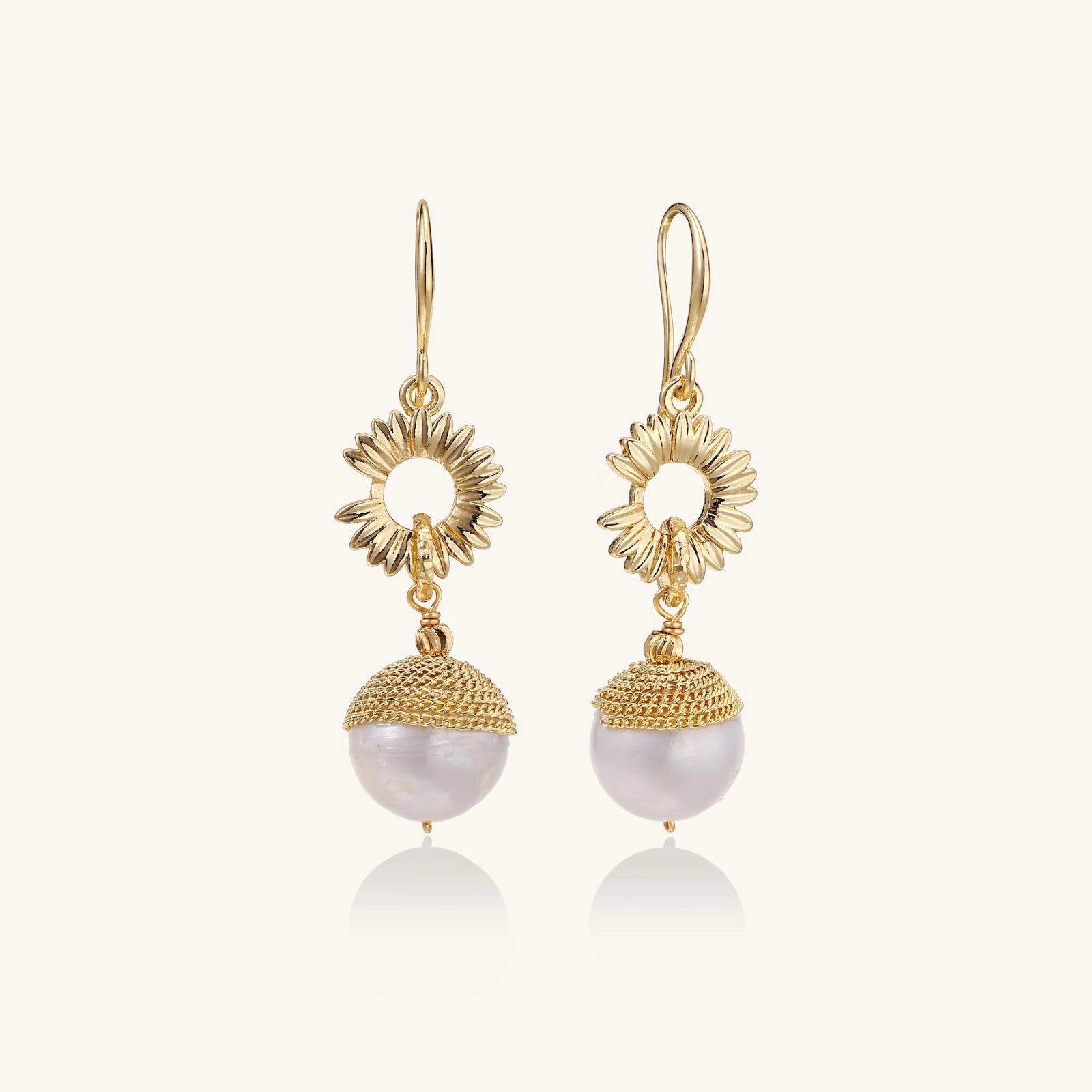 Gold earrings with pearl drops on a white background