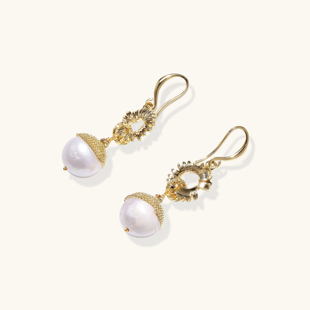 Gold earrings with pearl drops on a white background