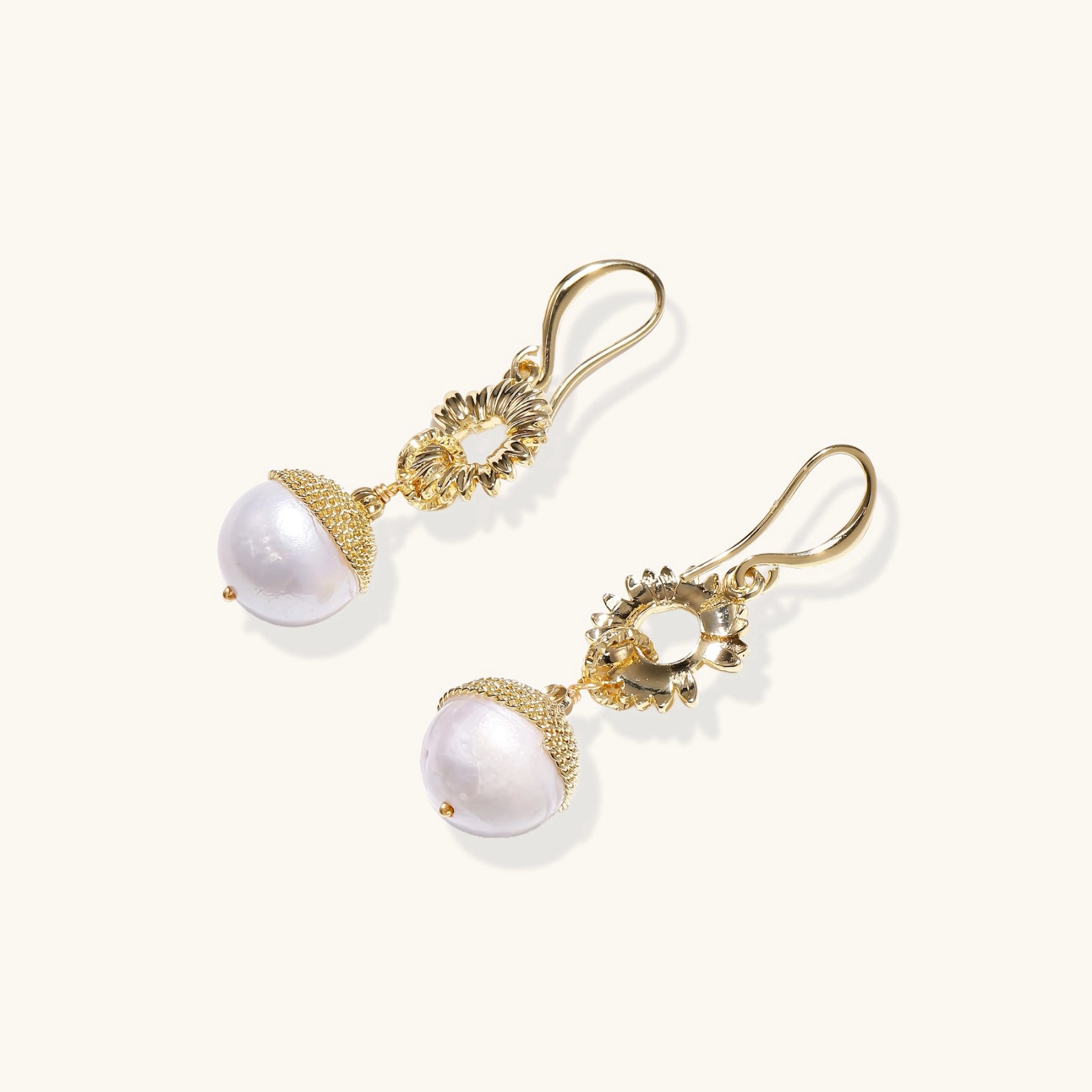 Gold earrings with pearl drops on a white background