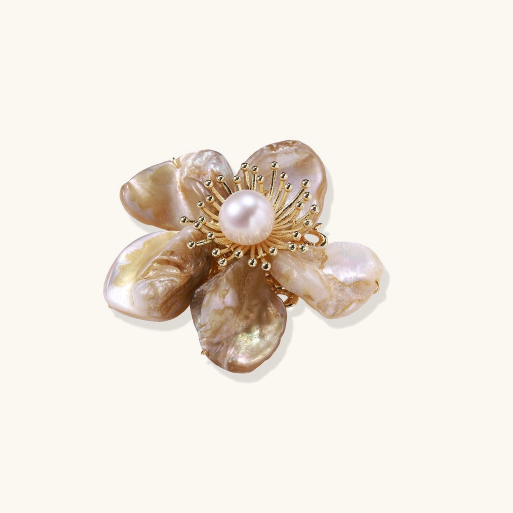 Decorative brooch with shell and pearl design on a white background
