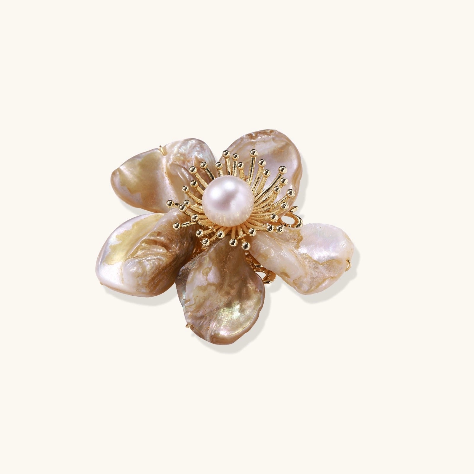 Decorative brooch with shell and pearl design on a white background