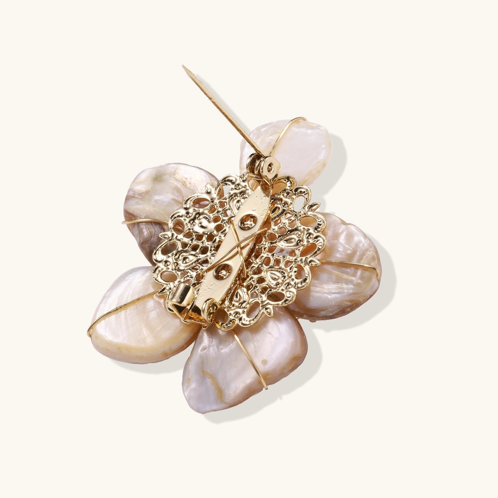 Gold and beige floral brooch on a white background