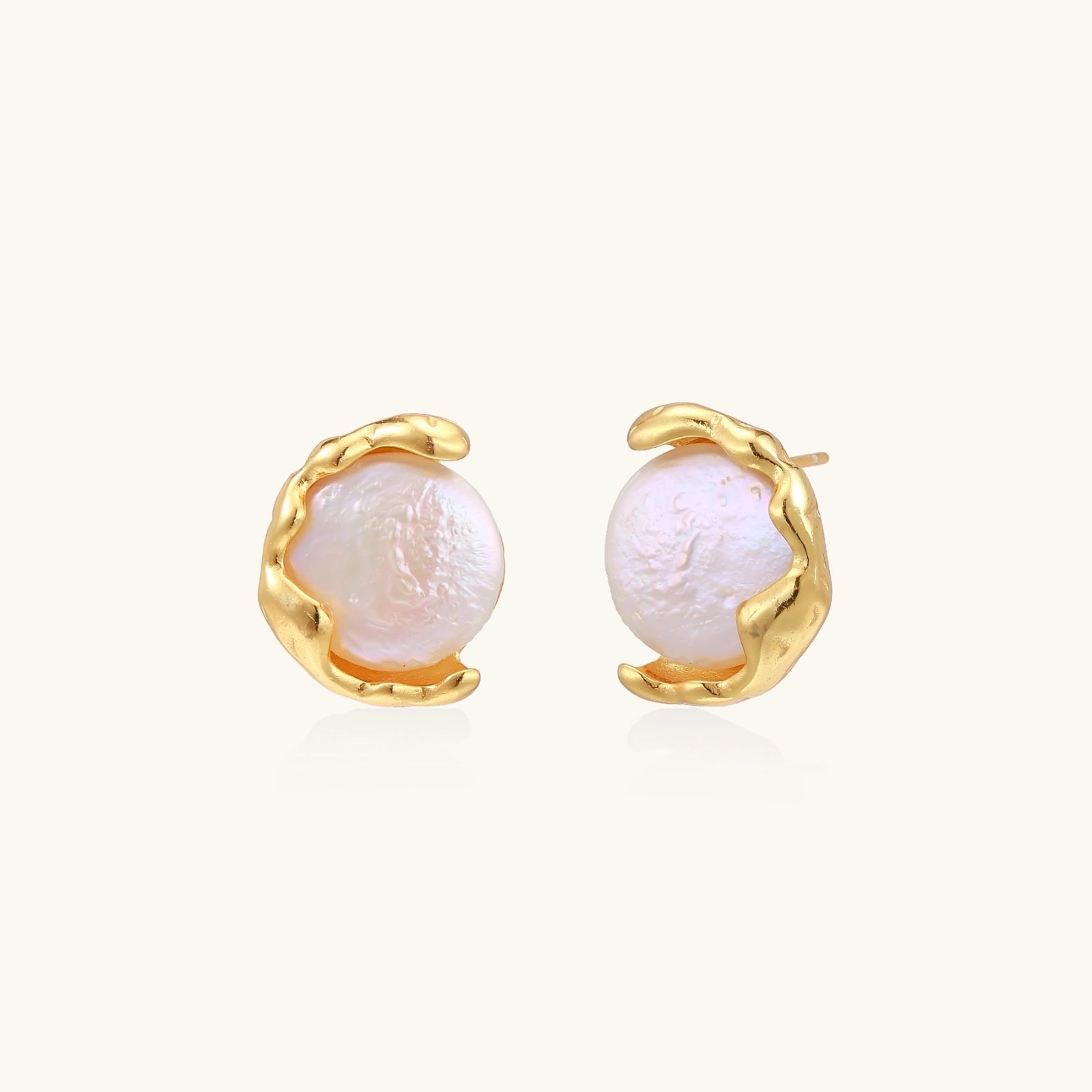Gold earrings with pearl centers on a white background