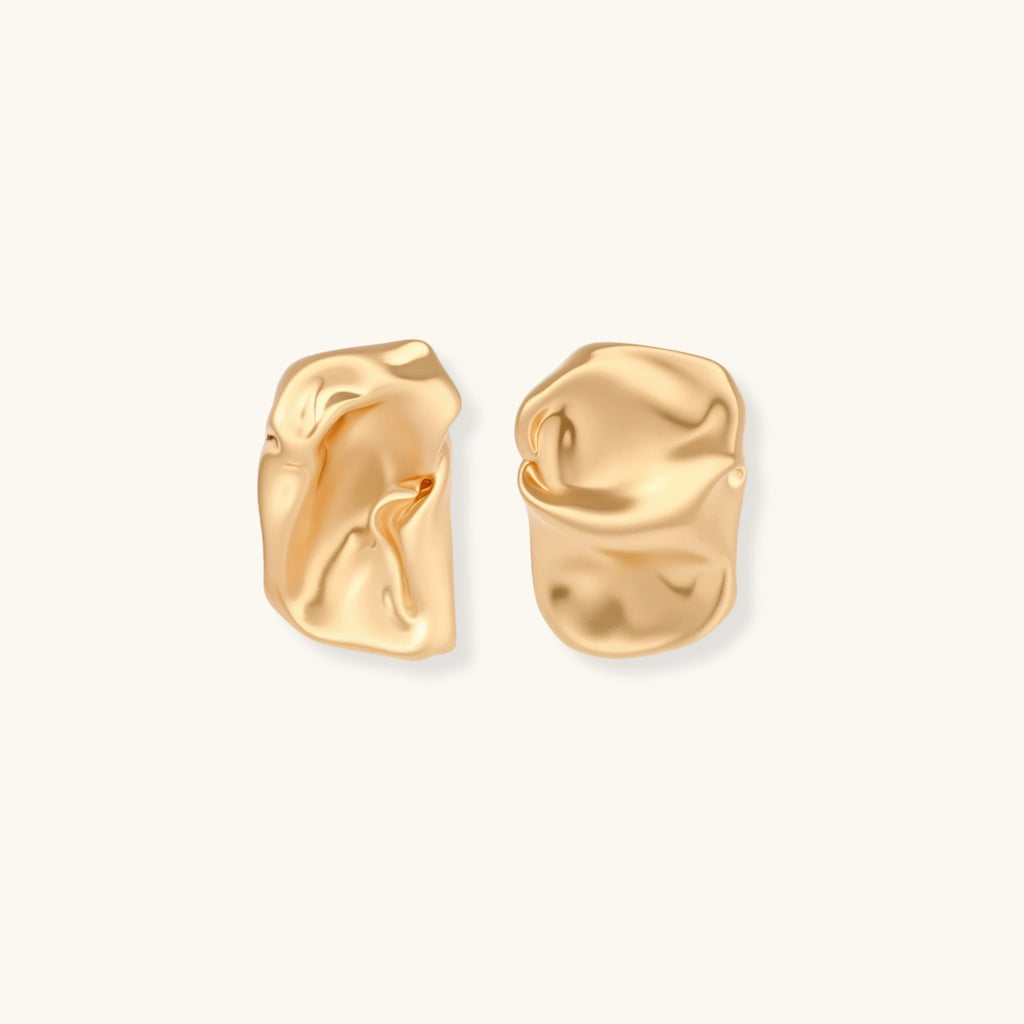 Pair of sculptural gold earrings on a light gray background