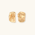Pair of sculptural gold earrings on a light gray background