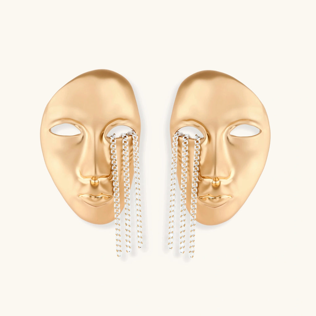Gold face-shaped earrings with chain drops on a white background