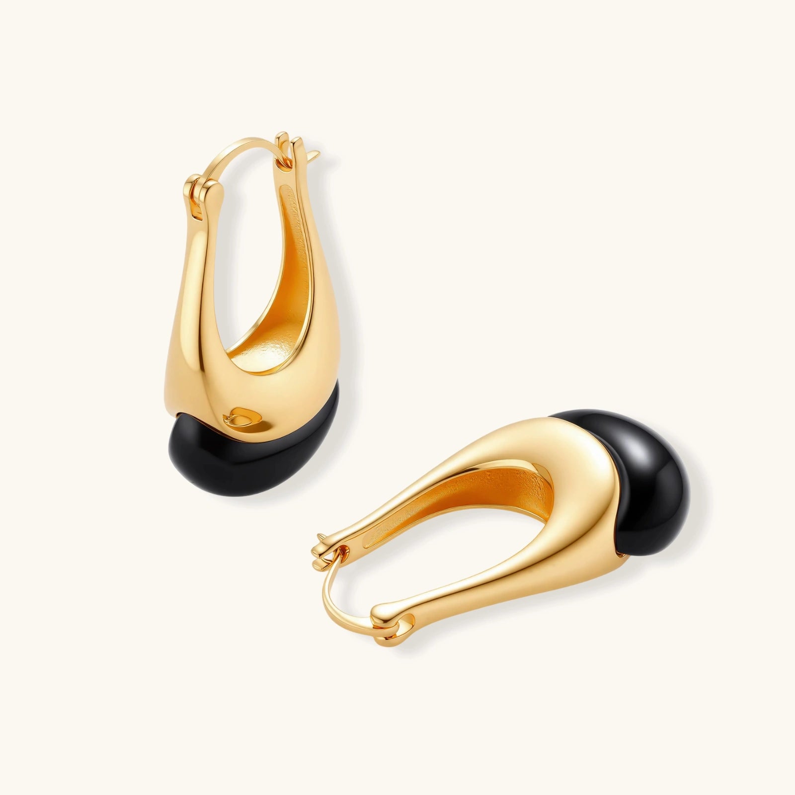 Gold hoop earrings with black spherical ends on a white background