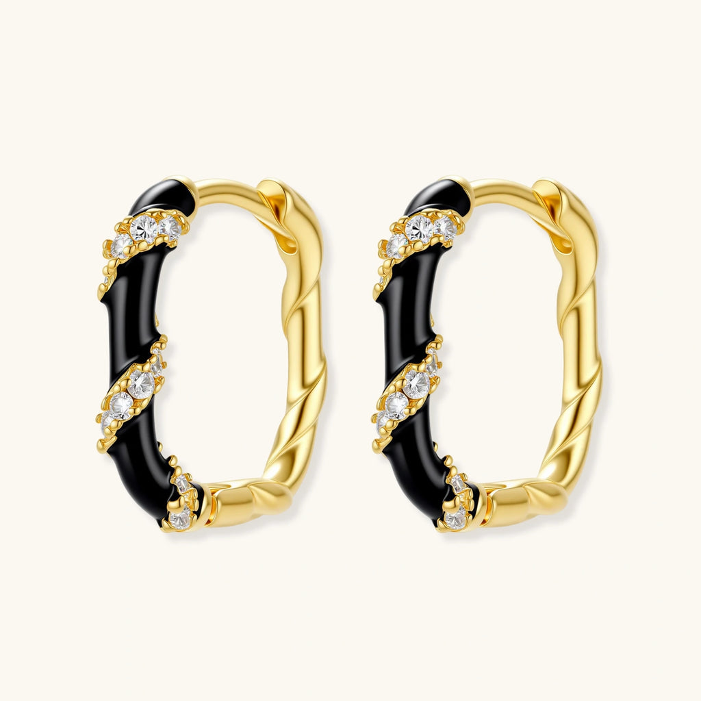 Gold hoop earrings with black and clear gemstones on a white background