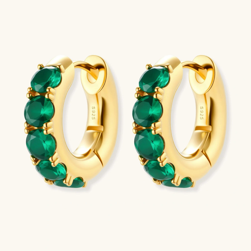Gold hoop earrings with green gemstones on a white background