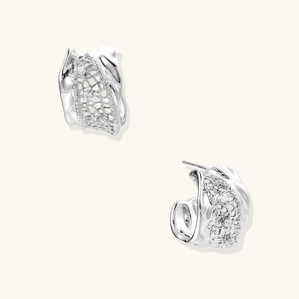 Pair of white gold plated earrings with clear gemstones and mesh like detail on a white background