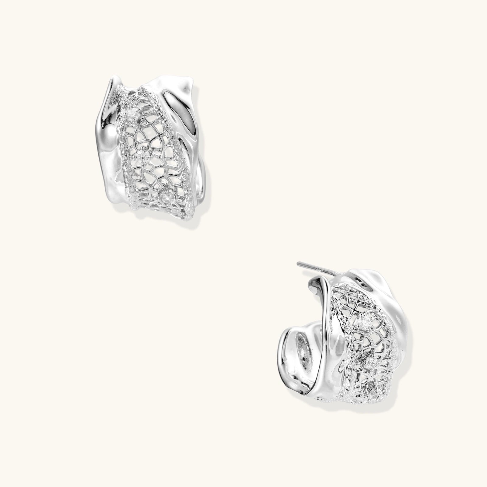 Pair of white gold plated earrings with clear gemstones and mesh like detail on a white background