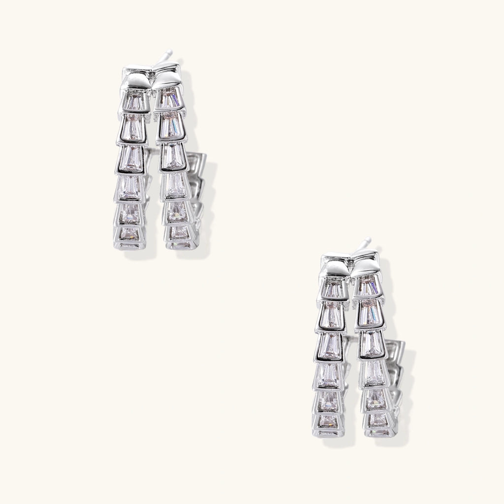 Pair of silver earrings with clear gemstones on a white background