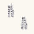 Pair of silver earrings with clear gemstones on a white background