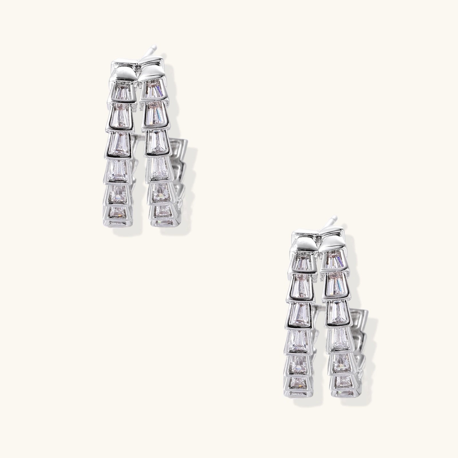 Pair of silver earrings with clear gemstones on a white background