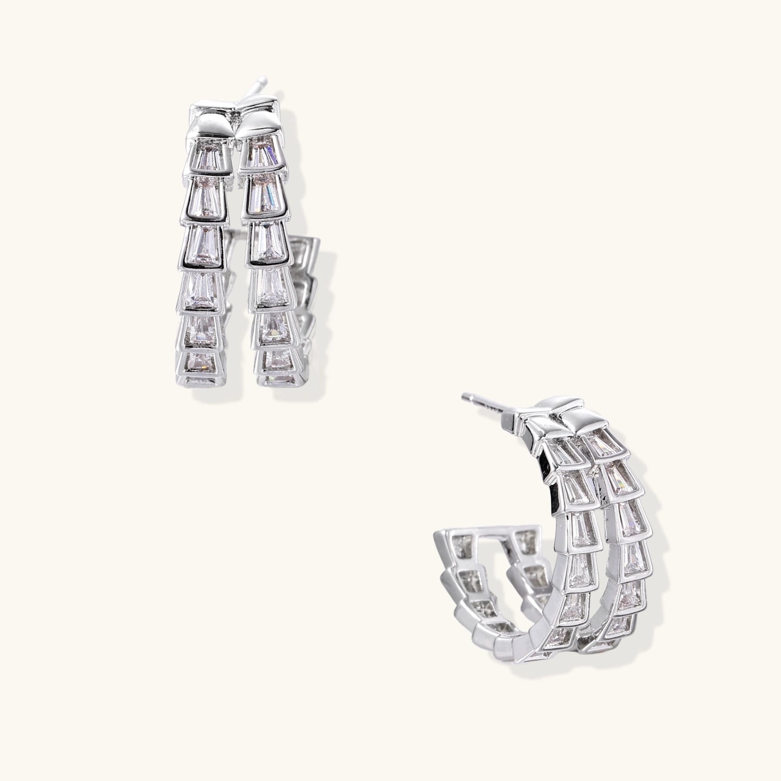 Pair of silver hoop earrings with clear gemstones on a white background