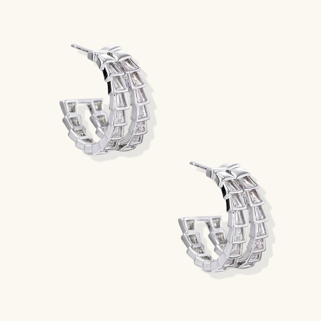 Pair of silver hoop earrings with clear gemstones on a white background