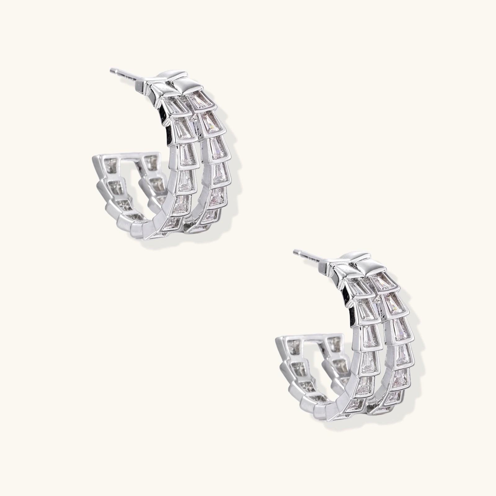 Pair of silver hoop earrings with clear gemstones on a white background