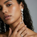 Close-up of a woman wearing silver floral earrings with a neutral background