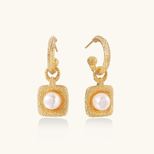 Gold earrings with pearl centers on a white background