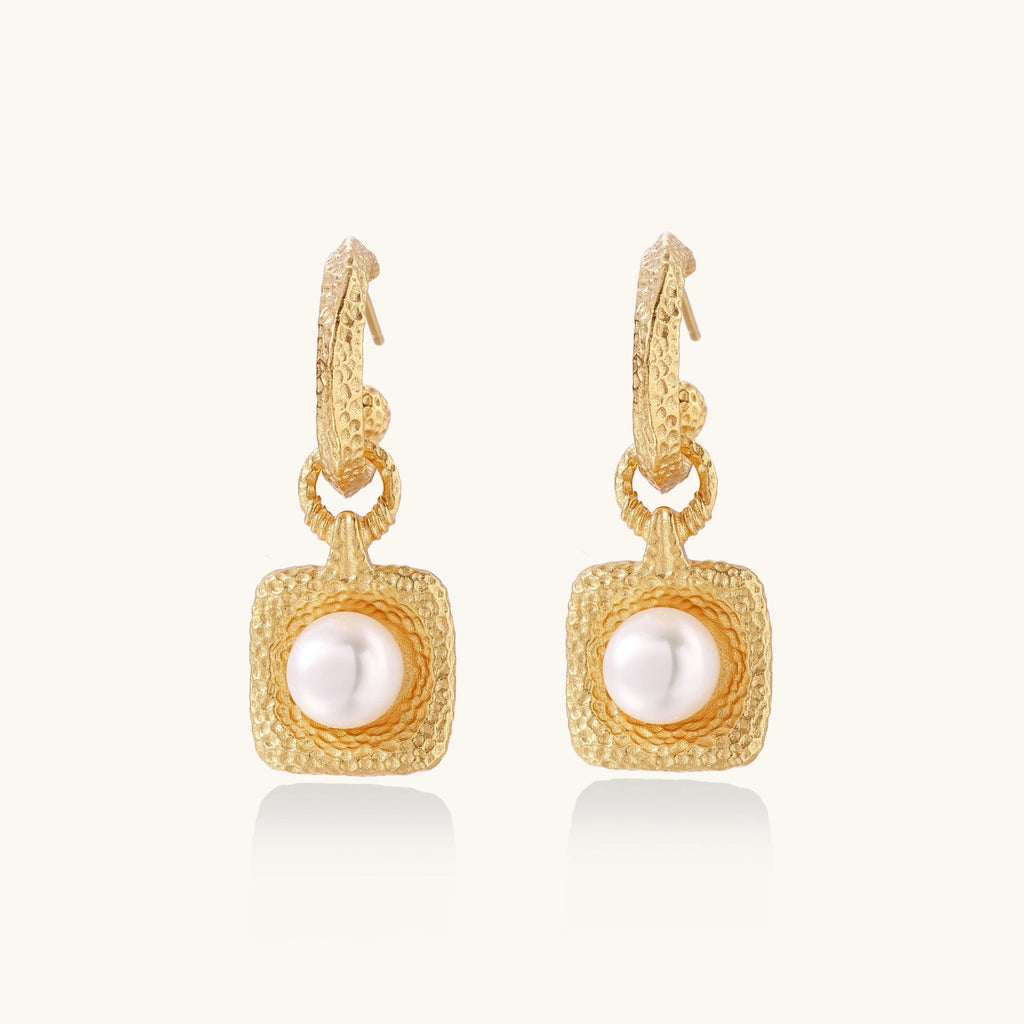 Gold earrings with pearl centers on a white background